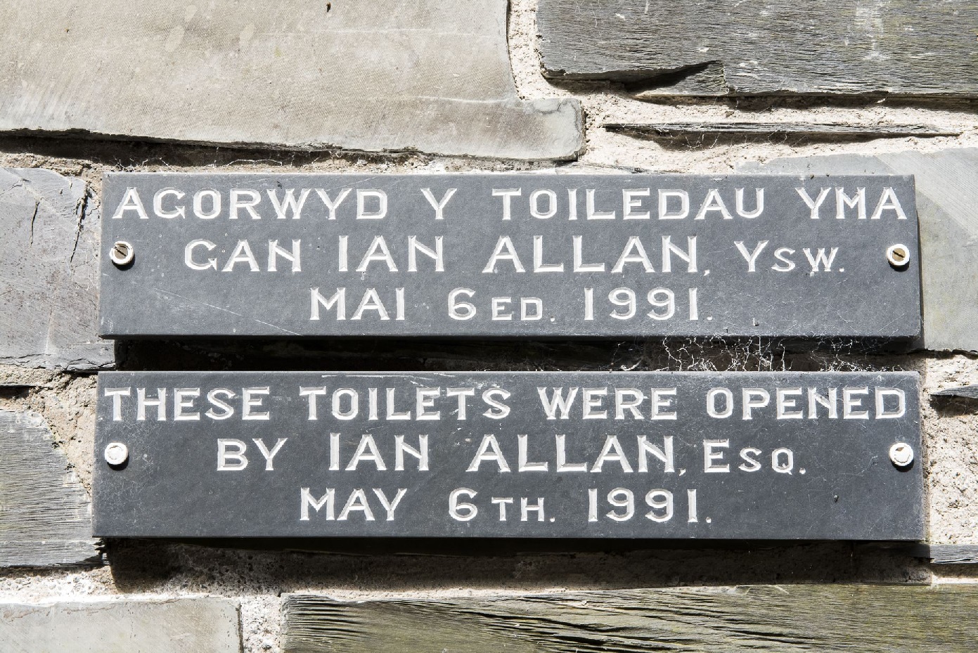 A sign on the Abergynolwyn toilet block in Welsh and English. Saying These toilets were opened by Ian Allen Esq. May 6th 1991.