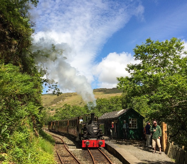 A steam train hauled by Tom Rolt pulling into Nant Gwernol station, the waiting room is shown on the right.