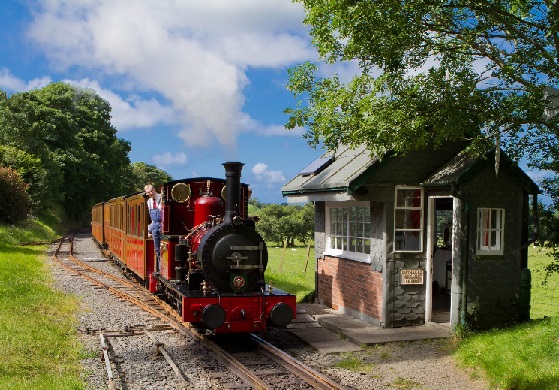 A steam train stationary next to the Brynglas block post with hills and blue sky behind.