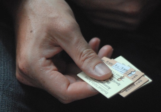 A close up hand holding four old Talyllyn tickets.