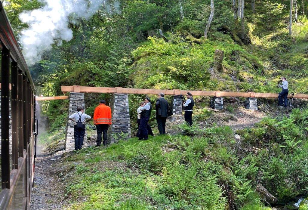 A group of people and a train by a slate water column.