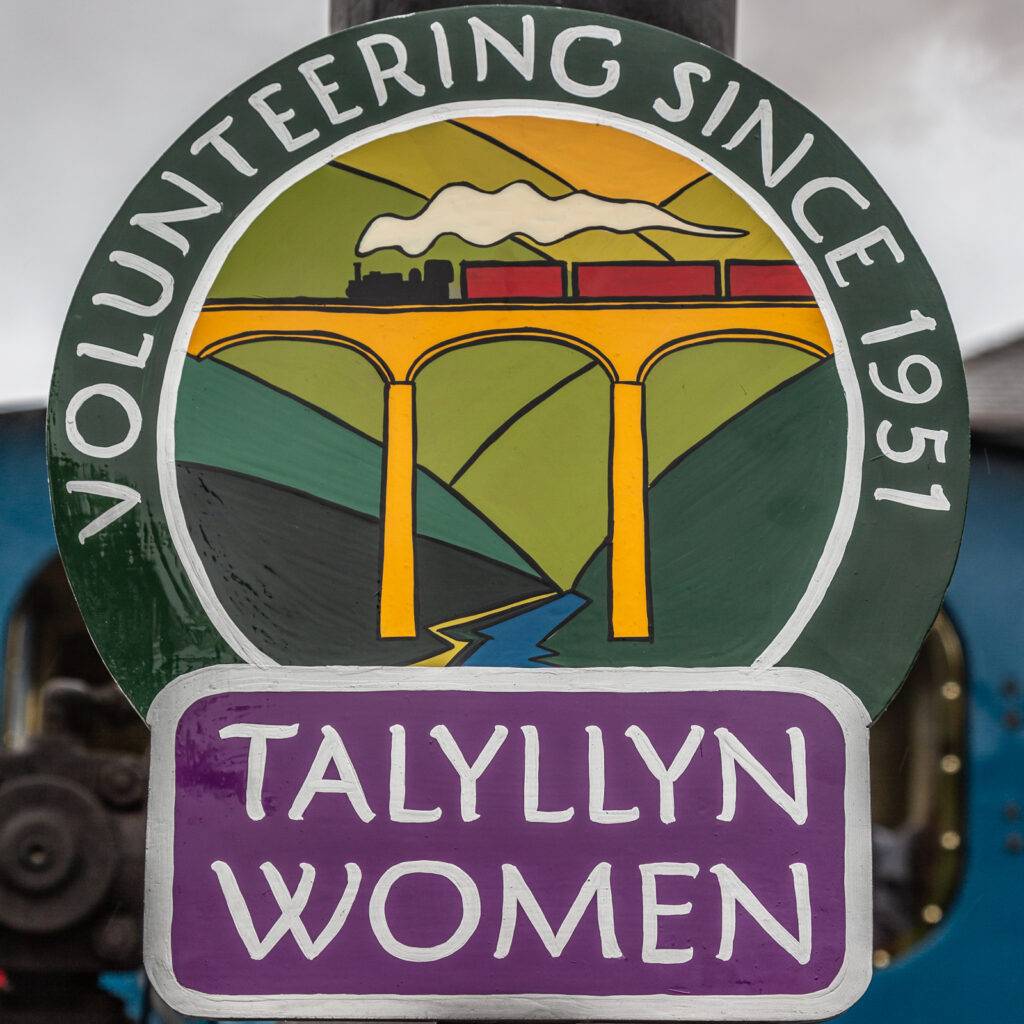 A wooden painted headboard with 'Talyllyn Women' text.