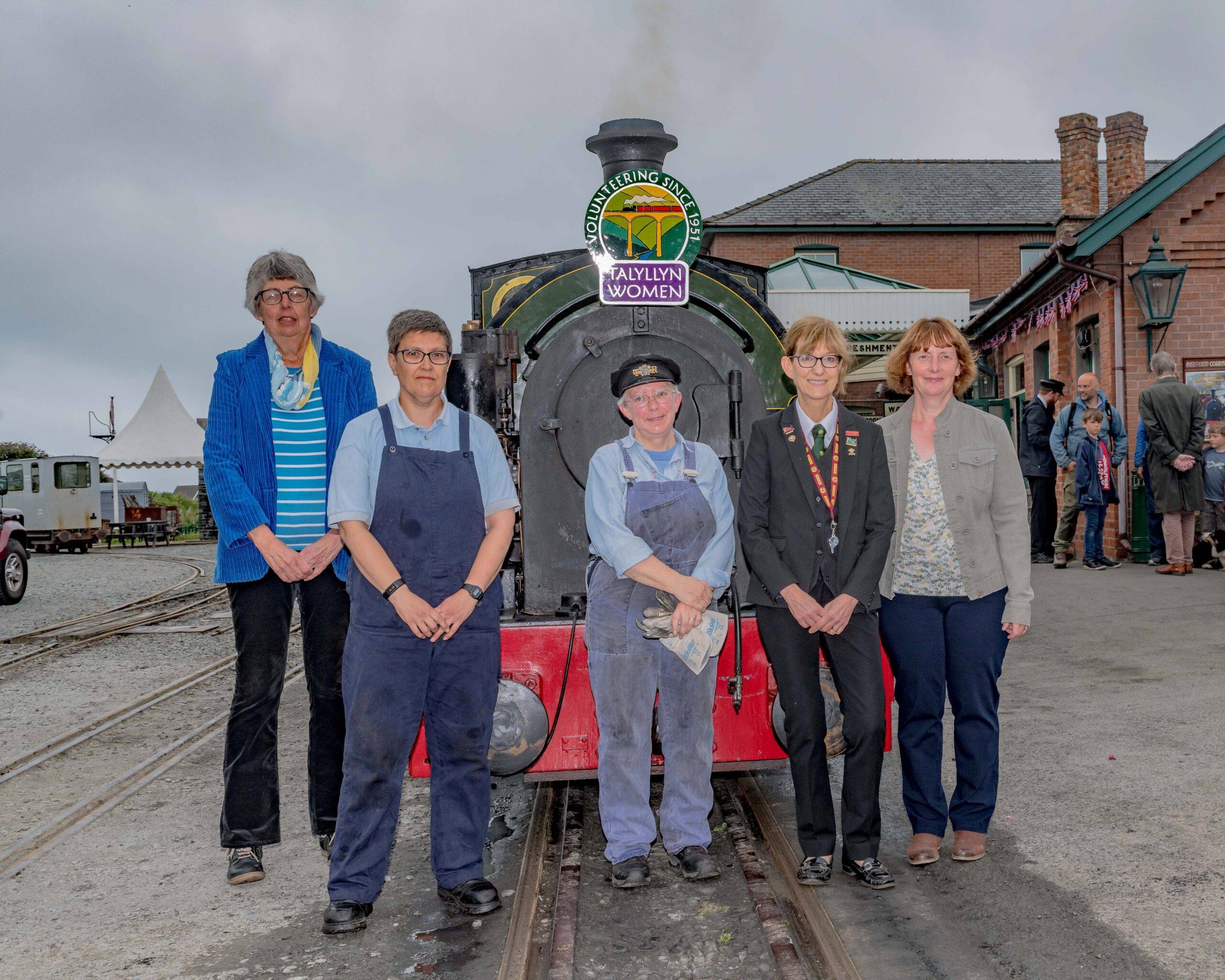 Five women stood in front of a steam engine.