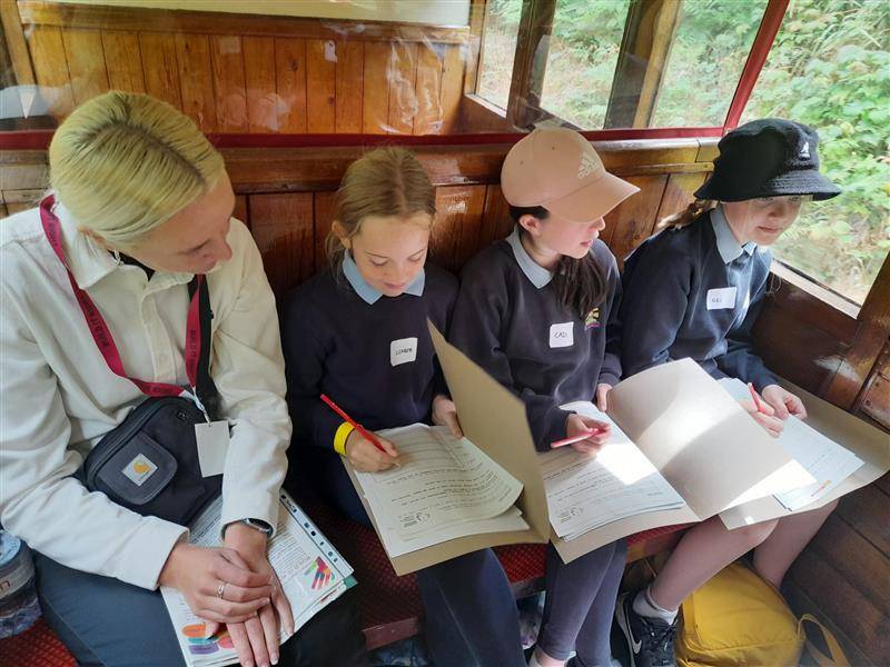 A group of children and one adult travelling in a railway carriage.