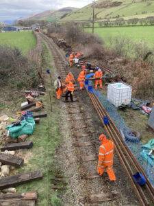 A large group of people removing track and sleepers from a railway line.