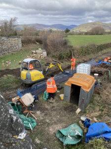 A digger being used to clear ballaset from a railway line.