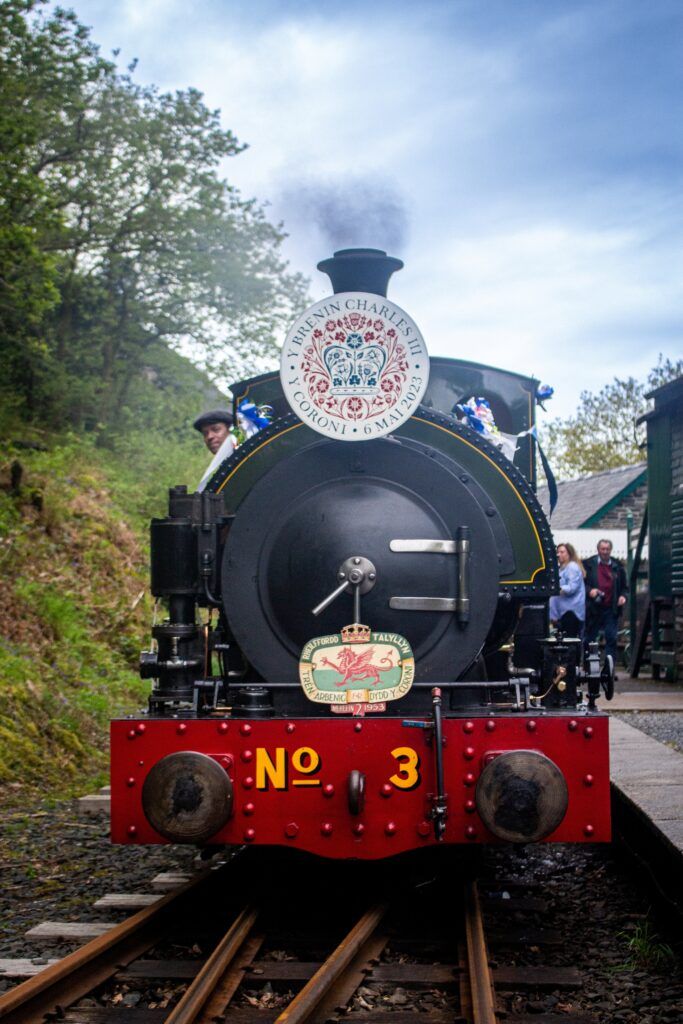 A steam train decortated with red, white and blue ribbons with an intricate headboard.