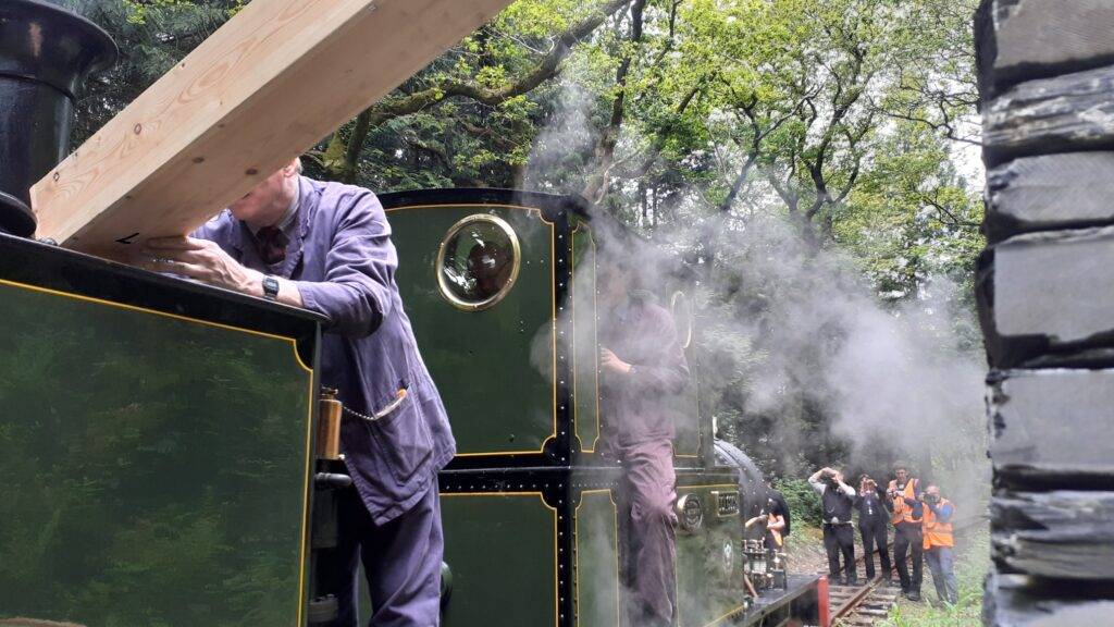A steam engine taking on water at a slate water column.